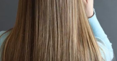 Saçlarını gri arka planda tarayan kadın, yakın plan.