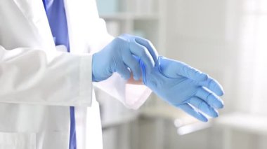 Doktor hastanede eldiven takıyor, yakın plan.