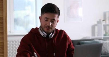 Kendi kendine çalışma. İçerideki masada ders sırasında not alan bir adam. Kamera aşağı iniyor