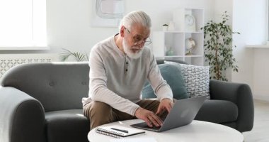 Üst düzey bir adam internette bilgisayarla kapalı bir masada öğreniyor. Kendi kendine çalışma.