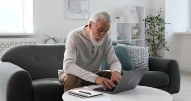 Üst düzey bir adam internette bilgisayarla kapalı bir masada öğreniyor. Kendi kendine çalışma.