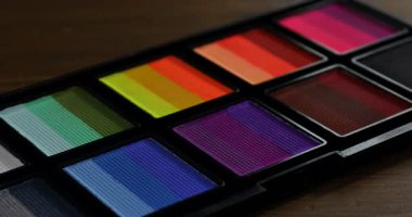 Ahşap masada yüz boyama için fırça ve palet kullanan kadın.