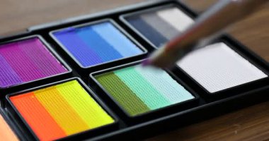 Ahşap masadaki yüz boyama için fırça ve palet kullanın.