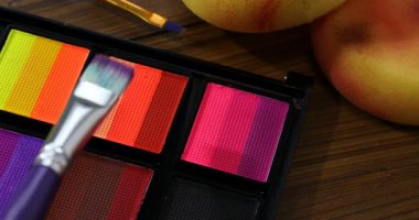 Ahşap masadaki yüz boyama için fırça ve palet kullanın.