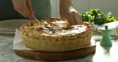 Bir kadın ahşap tahtadan lezzetli bir parça ev yapımı turta alıyor ve tabağa koyuyor, yakın plan.