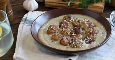 Krem soslu leziz köfteler, parmesan peyniri ve ahşap masada servis edilen otlar. Kamera sağa hareket ediyor