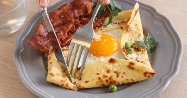 Ahşap masada yumurta ve pastırmalı leziz krep yiyen kadın, yakın plan. Breton galeti