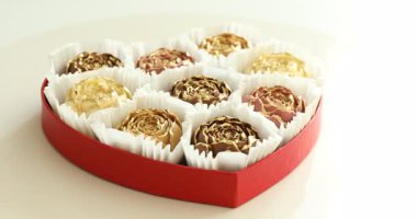 Çiçek şeklinde çikolatalı bonbonlar beyaz masanın üstünde, yakın plan. Kamera dönüyor