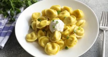 Yeşil soğanlı, maydanozlu ve çatallı lezzetli hamur tatlısı. Gri desenli masa, yakın plan.