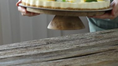 Lezzetli limonlu peynirli kekle tezgahı kapalı bir masa üzerine koyan kadın, yakın plan.