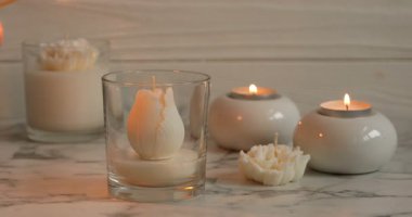 Beyaz mermer masada çiçek şeklinde mum yakan kadın, yakın plan.