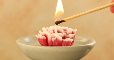 Bej arka planda çiçek şeklinde mum yakan kadın, yakın plan.