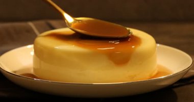 Masadaki lezzetli pudingin üzerine karamel sosu serpiştiriyorum.
