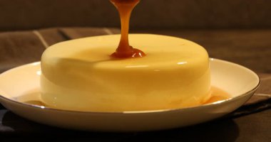 Masadaki lezzetli pudingin üzerine karamel sosu dök.