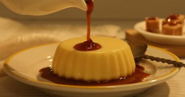 Hafif ahşap masadaki lezzetli pudingin üzerine karamel sosu dök.