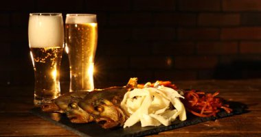 Farklı kurutulmuş balık atıştırmalıkları ve ahşap masada bira.