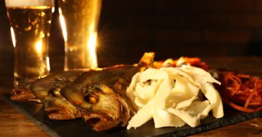 Different dried fish snacks and beer on wooden table, closeup