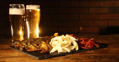 Biralı kadın ve farklı kurutulmuş balık atıştırmalıkları ahşap masada, yakın plan.