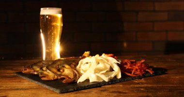 Biralı kadın ve farklı kurutulmuş balık atıştırmalıkları ahşap masada, yakın plan.