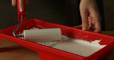 Masadaki tepsiden tekerlekli sandalyeye beyaz boya süren kadın, yakın plan.