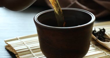 Ahşap masada fincana aromatik çay dök, yakın çekim.