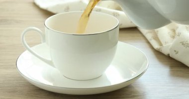 Ahşap masada fincana aromatik çay dök, yakın çekim.