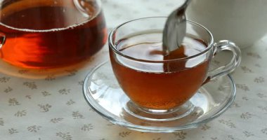 Masada aromatik çayla şekeri karıştırmak ve karıştırmak, yakın plan.