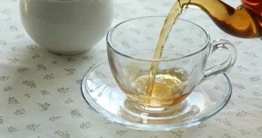 Çaydanlıktan fincana aromatik çay dök, yakın plan.