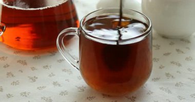 Masada aromatik çayla şekeri karıştırmak ve karıştırmak, yakın plan.