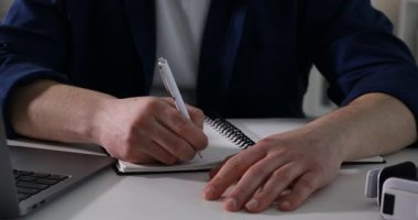 İçerideki masada ders sırasında not alan bir adam, yakın plan. Kendi kendine çalışma.