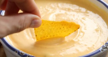 Nacho cipsini lezzetli peynir sosuna bandıran kadın, yakın plan.