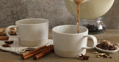 Ahşap masada fincanlara aromatik Masala çayı dökerek.