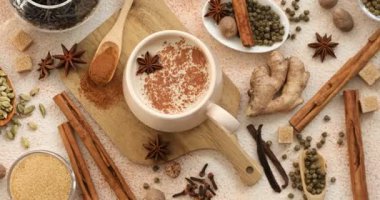 Fincanda Aromatik Masala çayı, baharatlar ve kahverengi şeker renkli masa, düz yatak. Kamera dönüyor
