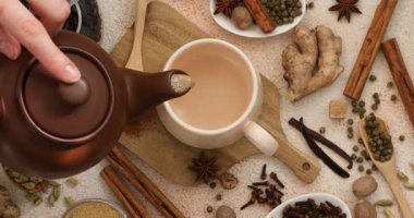 Kadın aromatik Masala çayını renkli masalarda fincana döküyor.
