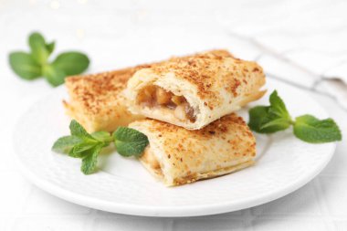 Lezzetli elmalı turtalar ve nane şekeri beyaz masada, yakın plan.