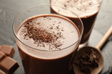 Lezzetli çikolatalı süt, siyah masanın üzerinde talaş ve parçalar, yakın plan.