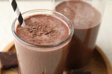 Lezzetli çikolatalı süt, beyaz masada talaş, yakın plan.