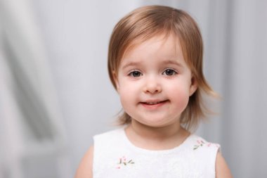 Açık gri arka planda şirin küçük bir kız.