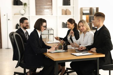 Ofisteki ahşap masada farklı aletlerle çalışan iş arkadaşları.