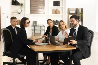 Ofisteki ahşap masada birlikte çalışan iş arkadaşları.