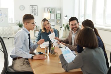 Ofisteki ahşap masada birlikte çalışan iş arkadaşları.