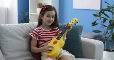 Evdeki kanepede gitar çalan tatlı bir kız.