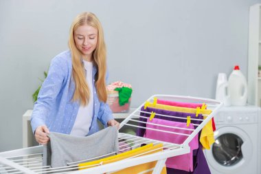 Güzel bir kadın temiz çamaşırları evdeki kuru askısına asıyor.