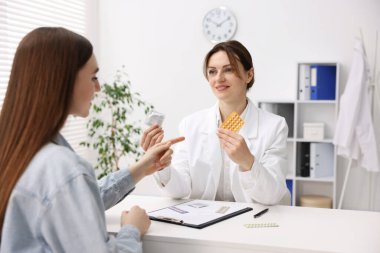 Jinekolog klinikte kadınlara farklı doğum kontrol ürünleri gösteriyor.