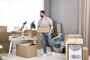 Taşınma günü. Yeni evinde karton kutuları olan bir adam.