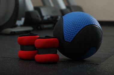 Mavi ilaç topu ve bilek ağırlıkları spor salonunda yerde, mesaj için yer var.