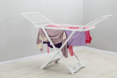 Gri duvarın yanında temiz çamaşırları olan kuru askı.