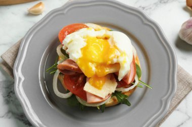 Lezzetli bir kahvaltı. Haşlanmış yumurta, jambon, domates, roka ve ekmek beyaz mermer masada, yakın plan.