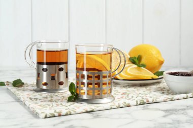 Beyaz mermer masada servis edilen metal tutacaklı çay bardakları.