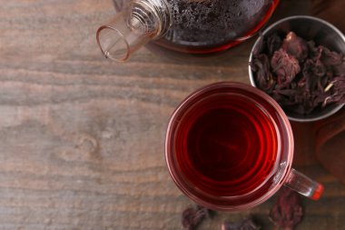 Lezzetli bardakta amber çayı, çaydanlık ve kuru roselle sepals tahta masada, düz yatak. Metin için boşluk